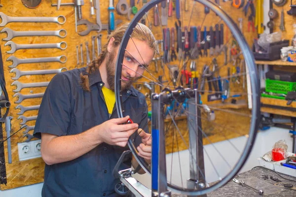 Ragazzo dagli occhi azzurri che ripara la bicicletta in officina Foto Stock