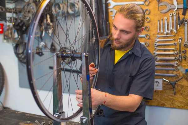 Ragazzo dagli occhi azzurri che ripara la bicicletta in officina Immagini Stock Royalty Free