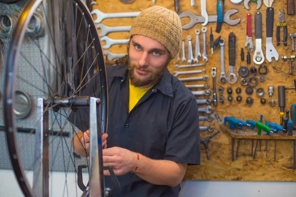 Ragazzo dagli occhi azzurri che ripara la bicicletta in officina Foto Stock Royalty Free