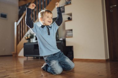 Beş yaşındaki tatlı çocuk güneşli bir günde oturma odasında gol attıktan sonra sevinç gösteriyor.