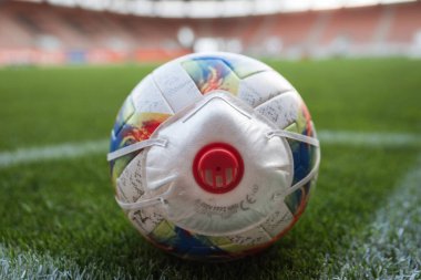 Futbol sahasının köşesinde maskeli top (sembol koronavirüs)