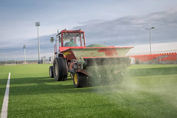 Yapay otlarla dolu bir futbol sahasına granüller dökülüyor..