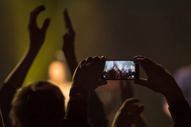 Akıllı telefon tutan ve kaydeden hayranlar veya konser sırasında fotoğraf çeken hayranlar
