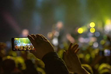 Akıllı telefon tutan ve kaydeden hayranlar veya konser sırasında fotoğraf çeken hayranlar