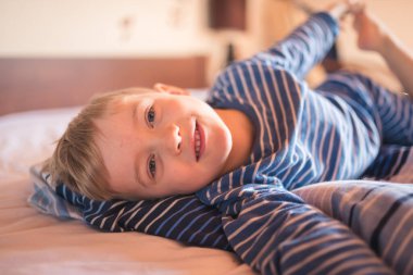 Beş yaşında, uyandıktan sonra yatakta gülümsüyor.