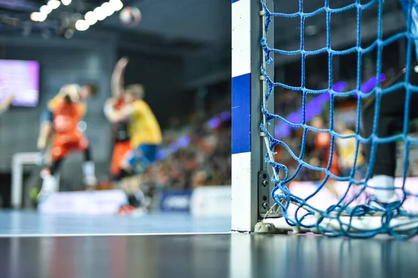 Hentbol kale direğinin ayrıntıları ve arka planda hentbol maçı.