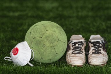 Futbol topu ve yüz maskeli ayakkabılar koronavirüs sembolüdür.