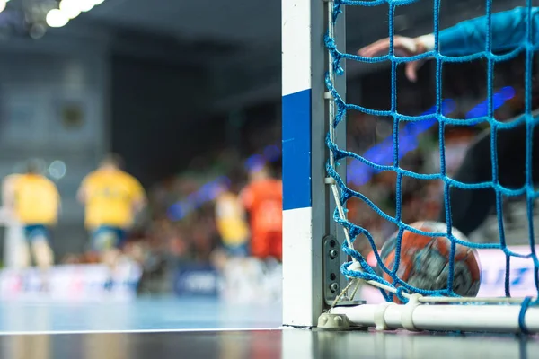 Hentbol kale direğinin ayrıntıları ve arka planda hentbol maçı.