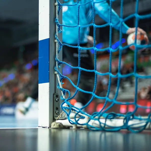 Hentbol kale direğinin ayrıntıları ve arka planda hentbol maçı.