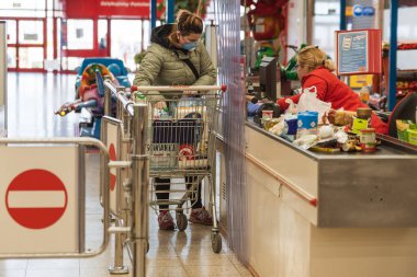 LUBIN, POLAND - 2 Nisan 2020. Auchan süpermarketindeki kasanın önündeki koronavirüs salgınından dolayı maske takan müşteri.