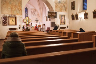 TYMOWA, POLAND - 10 Nisan 2020. Kilisedeki Tutku Ayini. Kutsal Cuma günündeki Kraliçemiz. Elinde haç tutan bir rahip. Covid-19 salgınından dolayı kilisede sadece 5 inançlı insan olabilir..