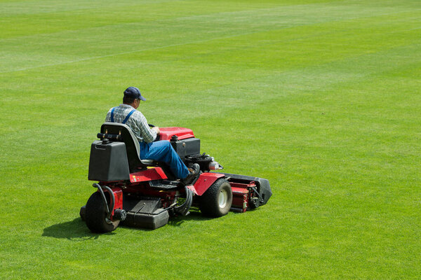  A man mowing the grass on a football stadium.