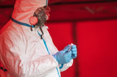 Yüz maskesi ve profesyonel üniformalı tıbbi personel Sars-Cov-2 'nin test çubuğu örneği. .