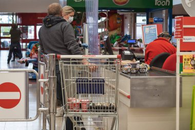 LUBIN, POLAND - 14 Mayıs 2020. Auchan süpermarketindeki kasanın önündeki müşteri. Koronavirüs salgınından dolayı insanların yüz maskeleri vardır..