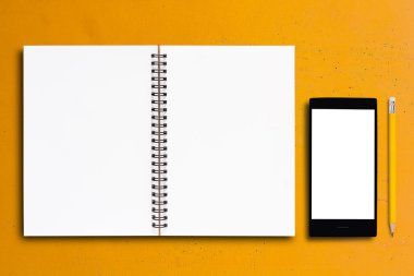 Defter ve sarı arka plan üstünde hareket eden telefon
