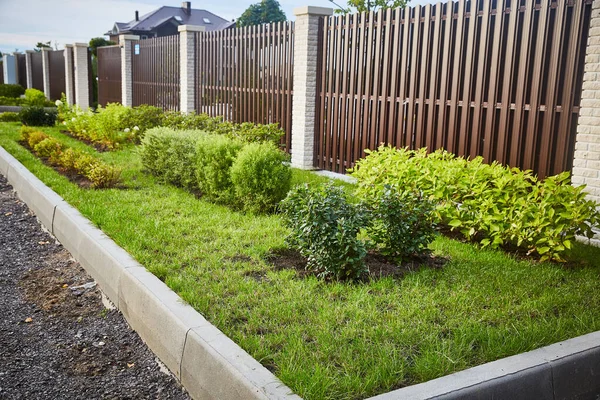 brown fence with decorative flower beds and a border stone