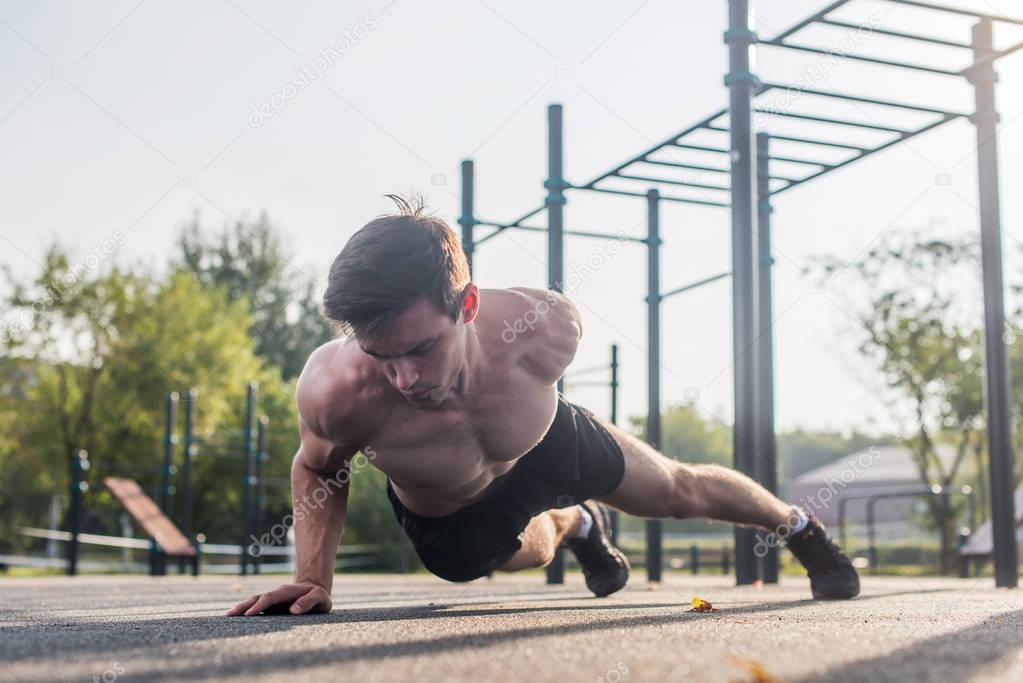 Athlete young man doing one-arm push-up exercise 