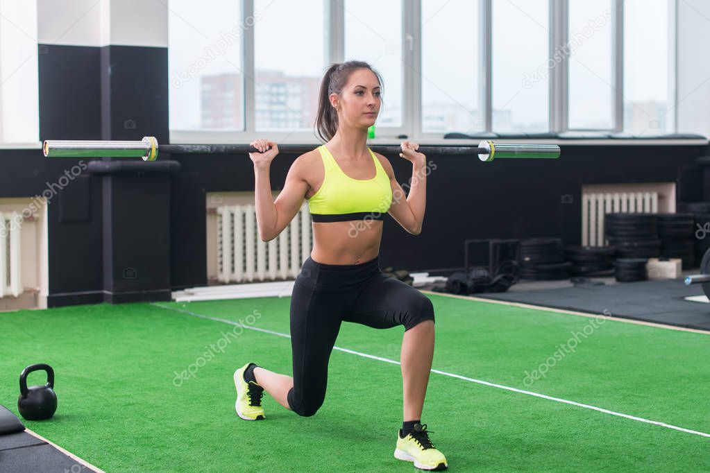 athletic woman doing lunges with barbell