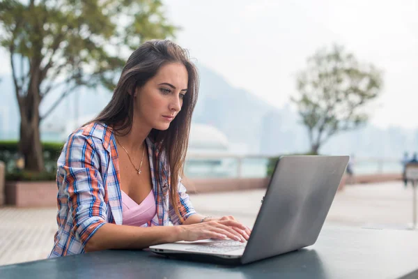 Mujer joven escribiendo en un ordenador portátil — Foto de Stock