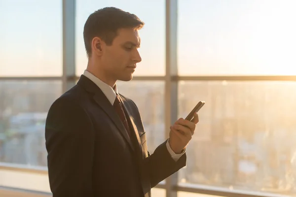 Homme avec smartphone dans un bureau moderne — Photo