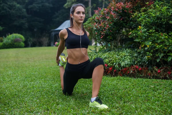 Fit girl doing kneeling quads stretch exercise in park — Stock Photo, Image