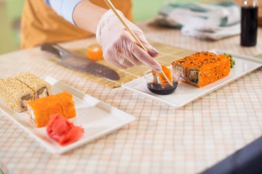 bir suşi roll chopsticks içinde tutarak eldiven içinde el 