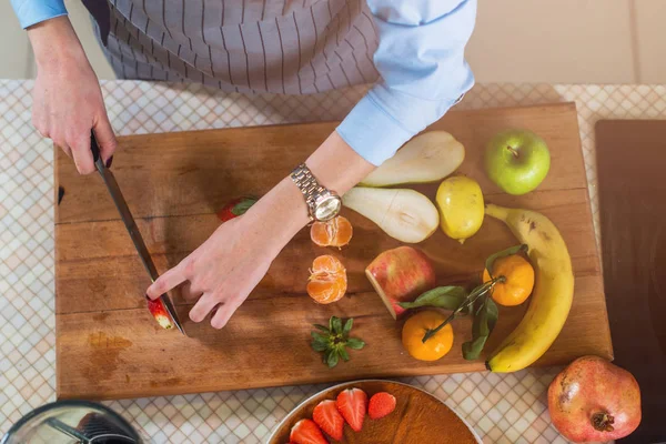 Prkénko s ovocem a ženských rukou — Stock fotografie