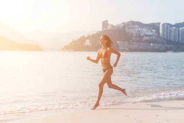 Apto atleta feminina vestindo biquíni correndo na praia — Fotografia de Stock