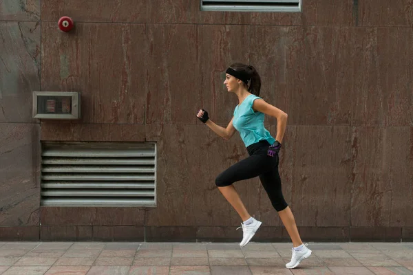 Mujer joven y deportiva corriendo en una acera —  Fotos de Stock