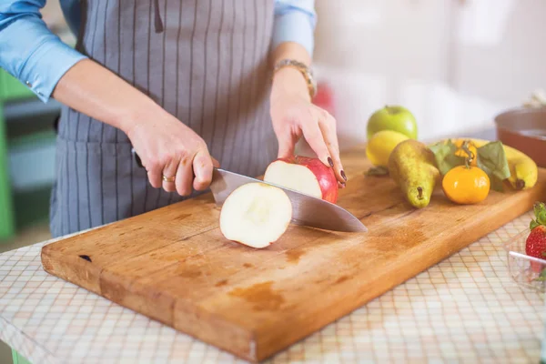 Hands cutting an apple on chopping board — Stock Photo, Image
