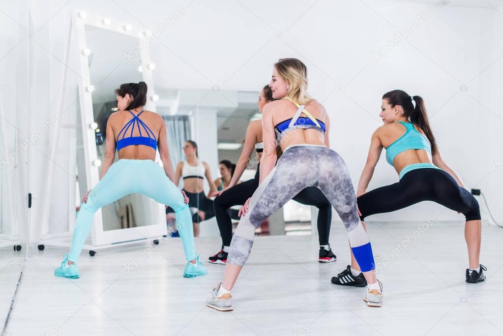 Rear view of fit young girls practicing twerk movements in dancing workshop