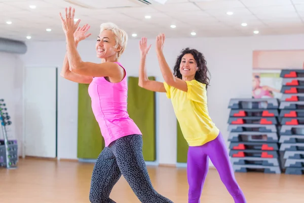 Gelukkig vrouwelijke atleten doen aerobics oefeningen of Zumba dans workout om gewicht te verliezen tijdens groepslessen in fitnesscentrum — Stockfoto