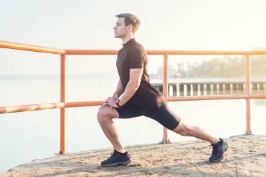 Fitness adam açık havada bacak kasları germe.
