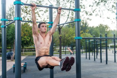 Egzersiz çalışma onun abs parkta dışarı asılı bacak yapan genç fitness erkek yükseltir.