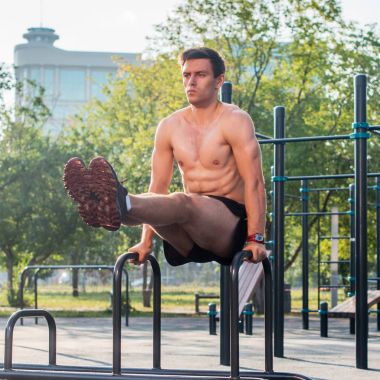 Bacak kaldırma abs egzersiz yaparak açık spor salonunda egzersiz genç güçlü atlet.
