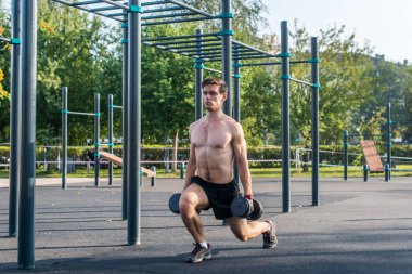 Genç kas fitness erkek modeli dumbbell hamle Park yapıyor.