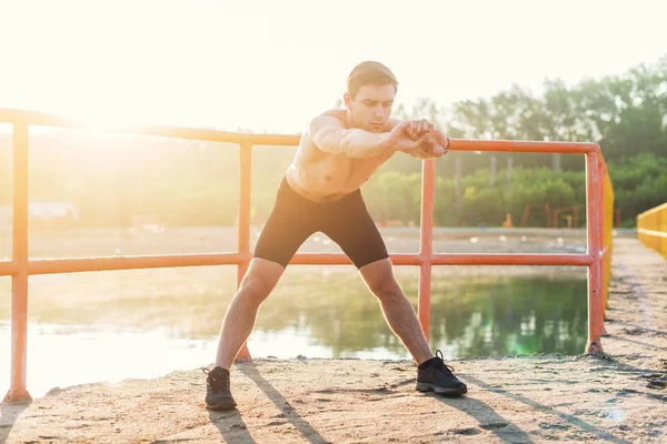 Молодой спортсмен наклоняется вперед и делает упражнения на растяжку . — стоковое фото
