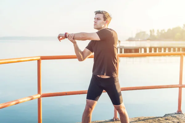 Jogger calentando ejercicio, estirando brazos y hombros. Fitness, deporte al aire libre . — Foto de Stock