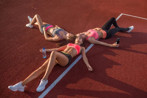 Tre flickor liggande på golvet avkopplande efter träning. — Stockfoto