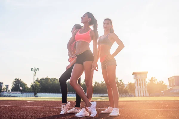 Grupp av fit unga idrottskvinnor stående i friidrottsarena och poserar. — Stockfoto
