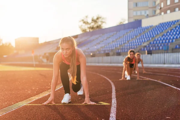 Mulheres sprinters na posição inicial pronto para a corrida em pista de corrida . — Fotografia de Stock