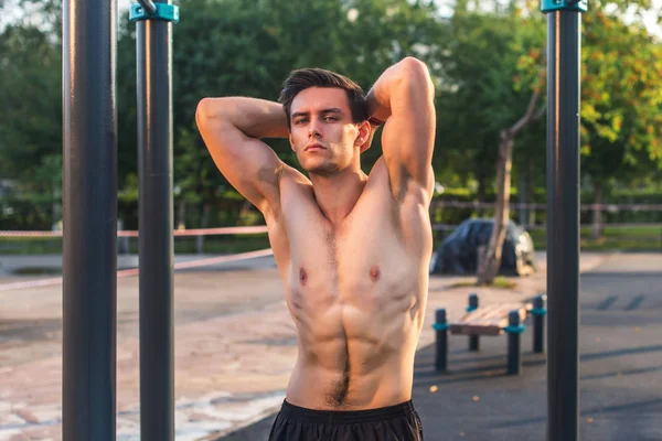 Fitnes uomo in posa sulla stazione di fitness di strada mostrando il suo corpo muscolare — Foto Stock