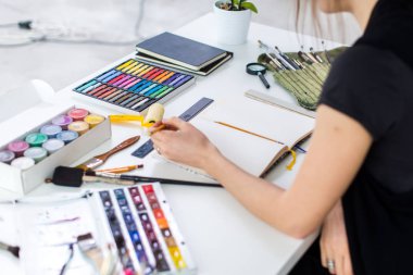 Yakın çekim Taslak çizim kalem kullanarak sketchbook bir kadın ressam görüş açısı. Sanatçı boya kalemi seti ile Sanat Atölyesi çizimi.
