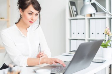 Onun işyerinde dizüstü bilgisayar kullanarak, bilgi tarama, dalga köpüğü enterne, yan görünüm portre işçisi kadın ofis.