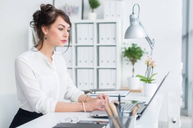 Ofiste çalışan, yazarak, bilgisayarı kullanan genç iş kadını. Konsantre kadın bilgi online arama