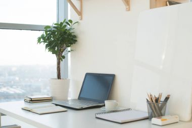 Yan görünümü resmi stüdyo çalışma alanı ile boş defter, laptop. Tasarımcı rahat çalışma tablosu, ev ofis.