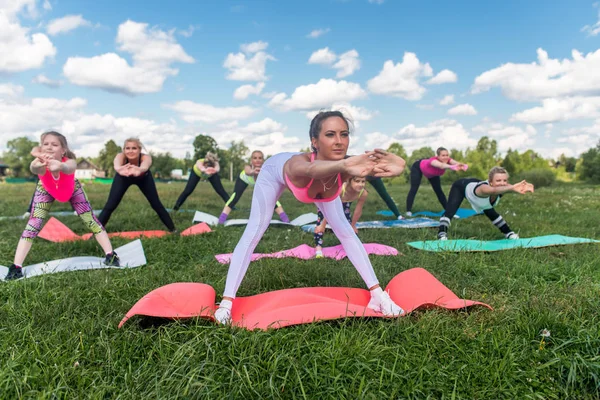 Porträtt av leende sportiga kvinnor gör stretching övningar fitness klass i parkmiljö. — Stockfoto