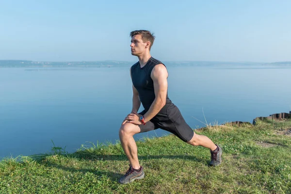 Junger, fitter Mann streckt Beine im Freien beim Ausfallschritt nach vorne. — Stockfoto