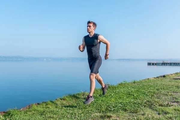 Přizpůsobit muž běžící na pláži ranní trénink venku v přírodě. — Stock fotografie