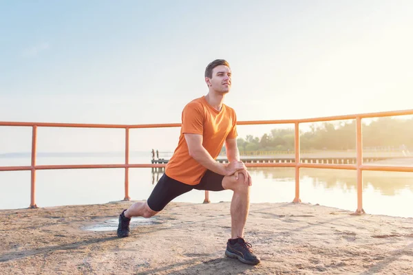 Junger, fitter Mann streckt Beine im Freien beim Ausfallschritt nach vorne. — Stockfoto